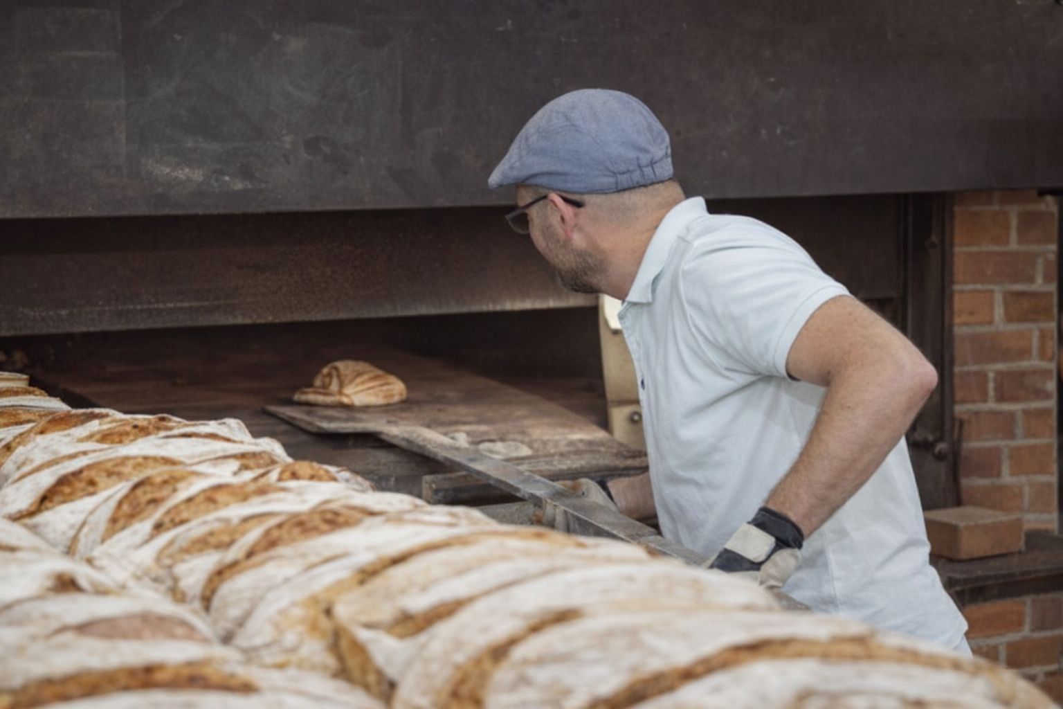 En bagare i Göteborg inspekterar bröd i en stor stenugn.